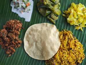Banana leaf rice is a traditional dish that originated in South India and is commonly served in Malaysia, Singapore, Sri Lanka, and other places with Indian diaspora. It consists of steamed rice or biryani served on a banana leaf with a variety of side dishes, such as curries, vegetables, pickles, papadum, and chutneys.